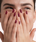 Close-up of a woman with Pink Gellac 334 Pomegranate Red manicured nails near her face.