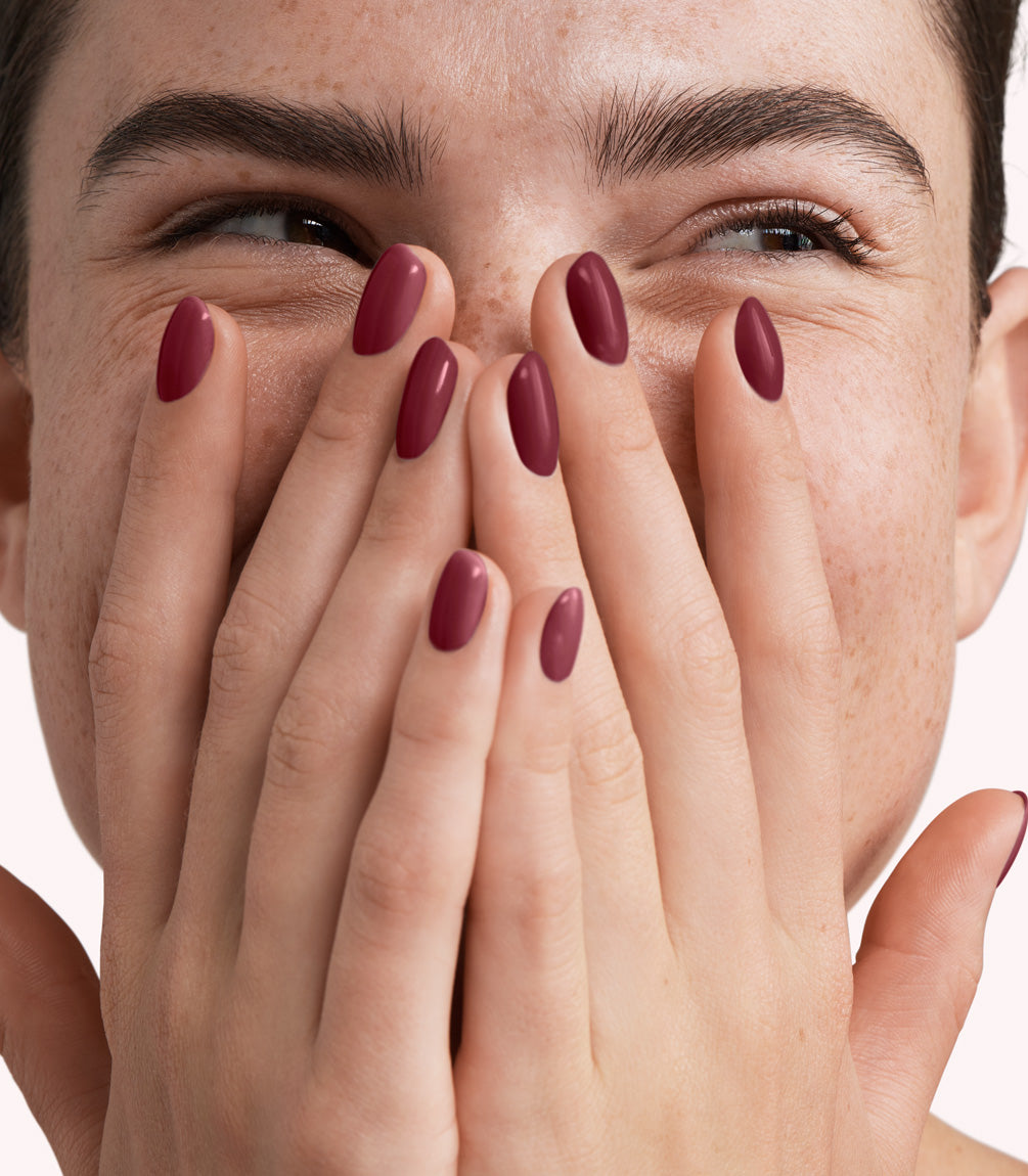 Close-up of a woman with Pink Gellac 334 Pomegranate Red manicured nails near her face.