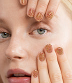 Close-up of a woman with Pink Gellac 335 Magical Gold manicured nails near her face.