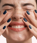 Close-up of a woman with Pink Gellac 338 Classic Blue manicured nails near her face.