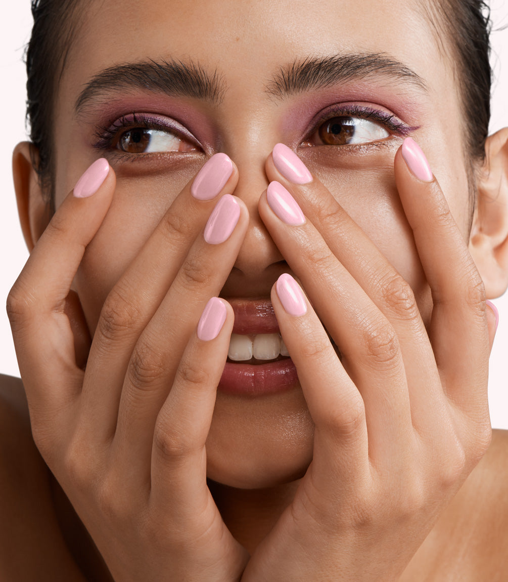 Close-up of a woman with Pink Gellac 346 Pleasant Pearl manicured nails near her face.