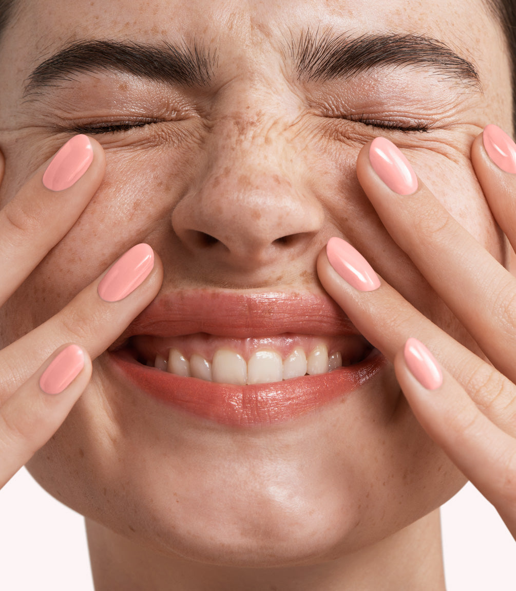Close-up of a woman with Pink Gellac 352 Neon Peach manicured nails near her face.