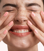 Close-up of a woman with Pink Gellac 352 Neon Peach manicured nails near her face.