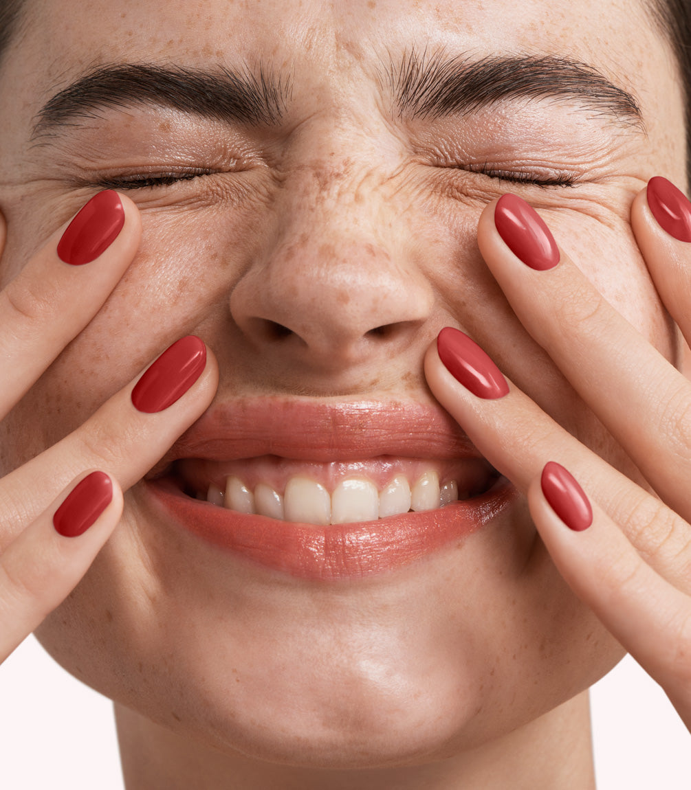 Close-up of a woman with Pink Gellac 353 Chili Red manicured nails near her face.