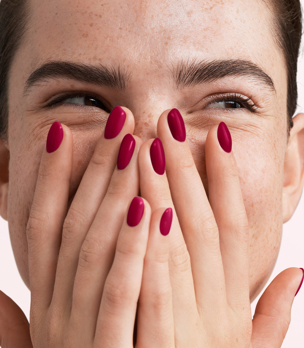 Close-up of a woman with Pink Gellac 355 Royal Red manicured nails near her face.