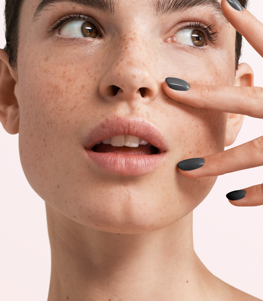 Close-up of a woman with Pink Gellac 358 Dove Grey manicured nails near her face.