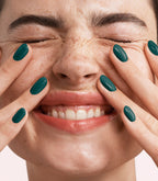 Close-up of a woman with Pink Gellac 361 Authentic Teal manicured nails near her face.