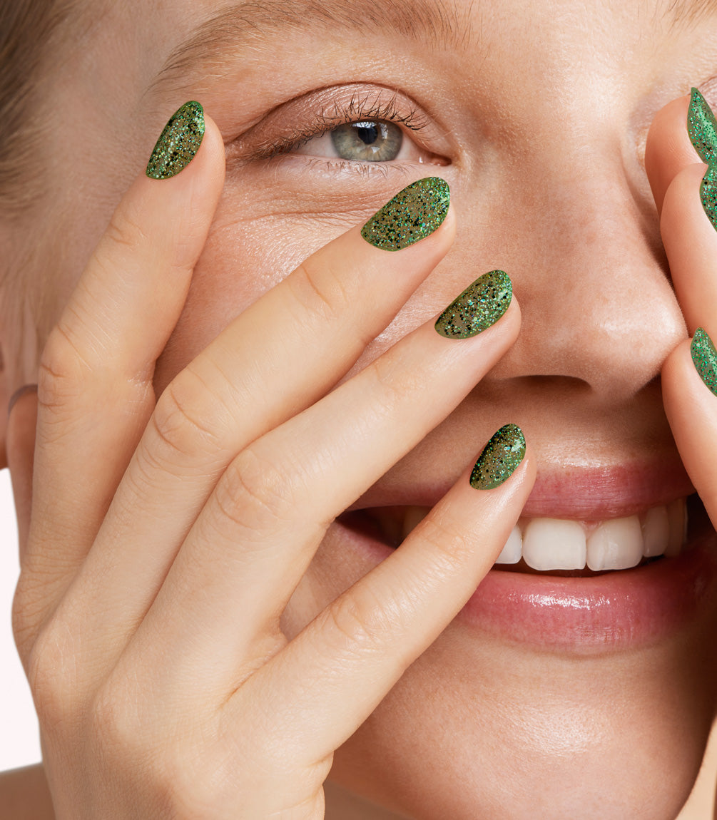 Close-up of a woman with Pink Gellac 362 Glistening Green manicured nails near her face.