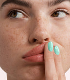 Close-up of a woman with Pink Gellac 365 Angelic Aqua manicured nails near her face.