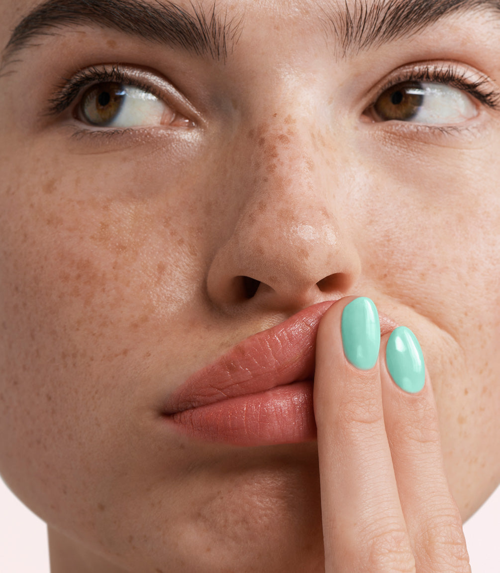 Close-up of a woman with Pink Gellac 365 Angelic Aqua manicured nails near her face.