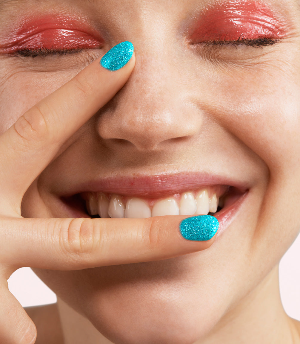 Close-up of a woman with Pink Gellac 366 Fortune Blue manicured nails near her face.