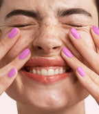 Close-up of a woman with Pink Gellac 367 Secret Purple manicured nails near her face.