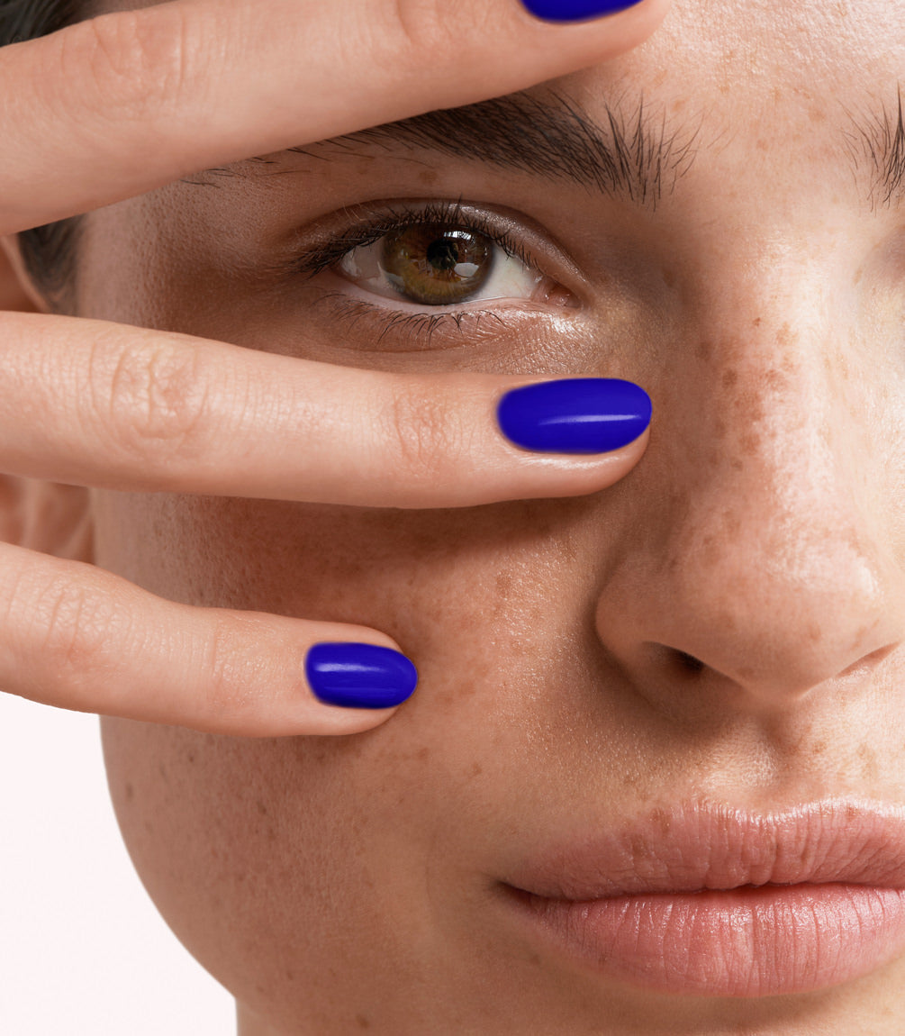 Close-up of a woman with Pink Gellac 373 Royal Blue manicured nails near her face.