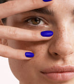Close-up of a woman with Pink Gellac 373 Royal Blue manicured nails near her face.