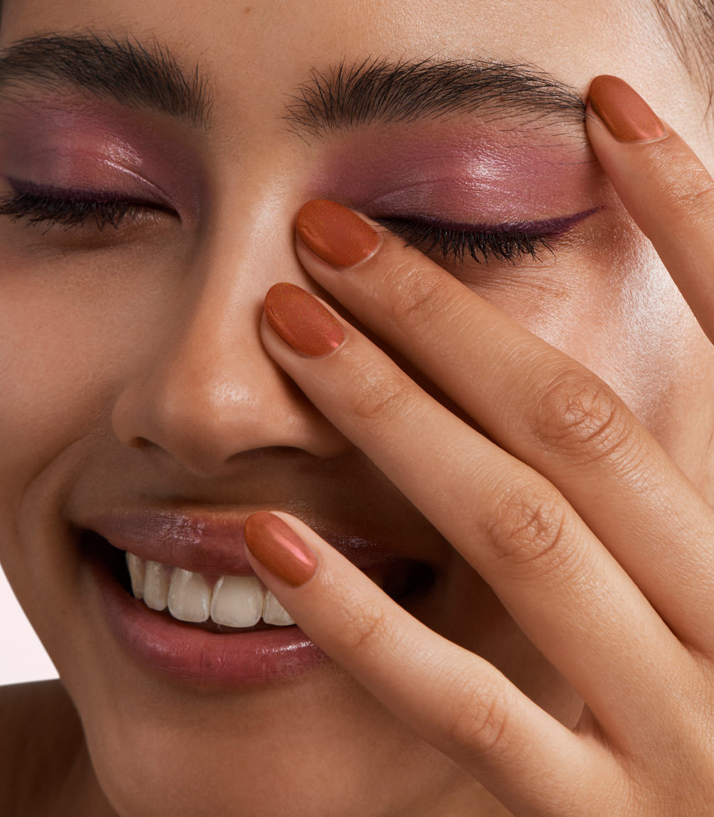 Close-up of a woman with Pink Gellac 378 Ginger Gold manicured nails near her face.