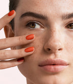 Close-up of a woman with Pink Gellac 379 Terra Orange manicured nails near her face.