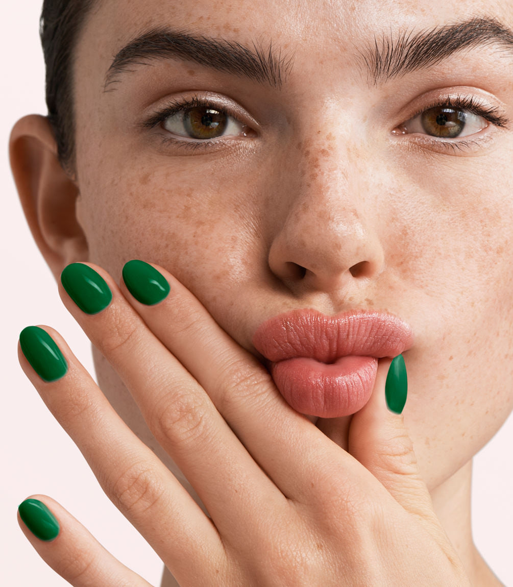Close-up of a woman with Pink Gellac 385 Pine Green manicured nails near her face.