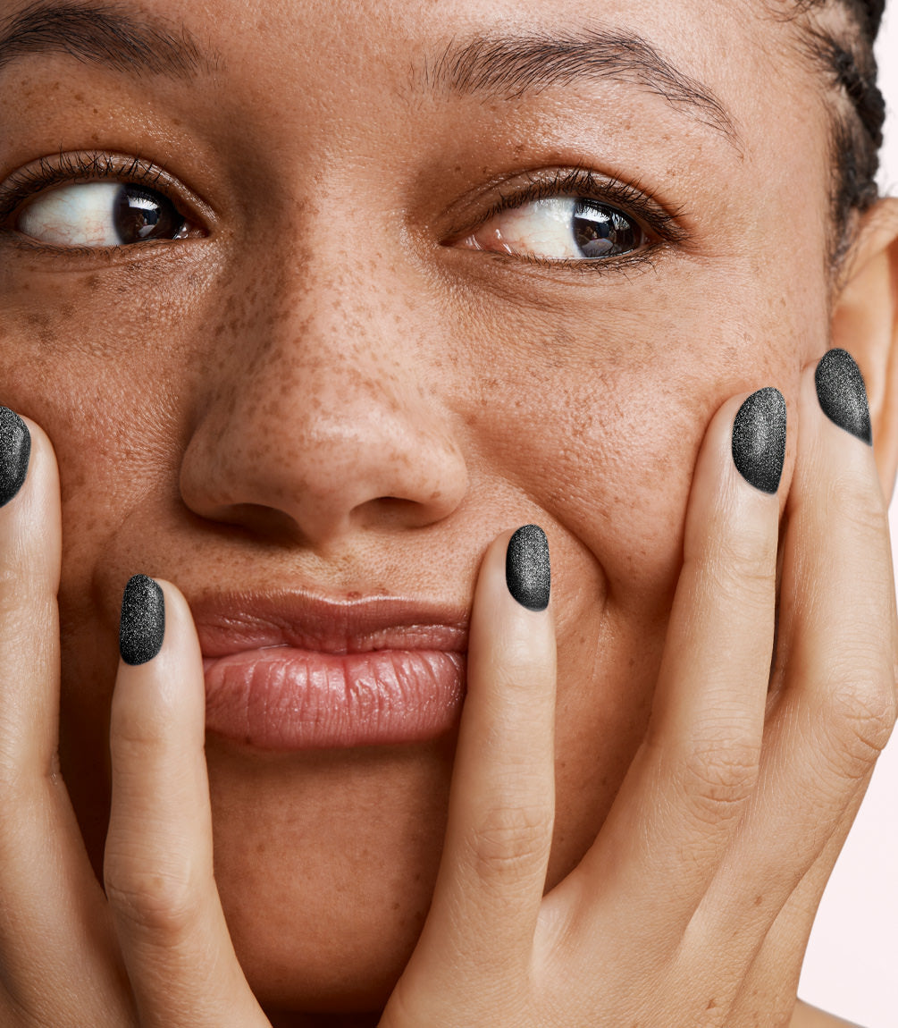 Close-up of a woman with Pink Gellac 386 Twinkling Black manicured nails near her face.