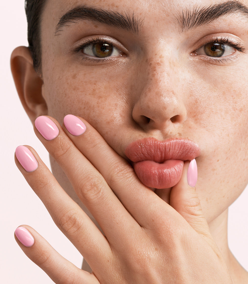 Close-up of a woman with Pink Gellac 388 Rosewater Pink manicured nails near her face.