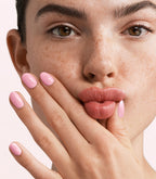 Close-up of a woman with Pink Gellac 388 Rosewater Pink manicured nails near her face.