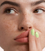 Close-up of a woman with Pink Gellac 390 Chilled Lime manicured nails near her face.