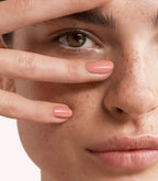 Close-up of a woman with Pink Gellac 399 Papaya Pink manicured nails near her face.