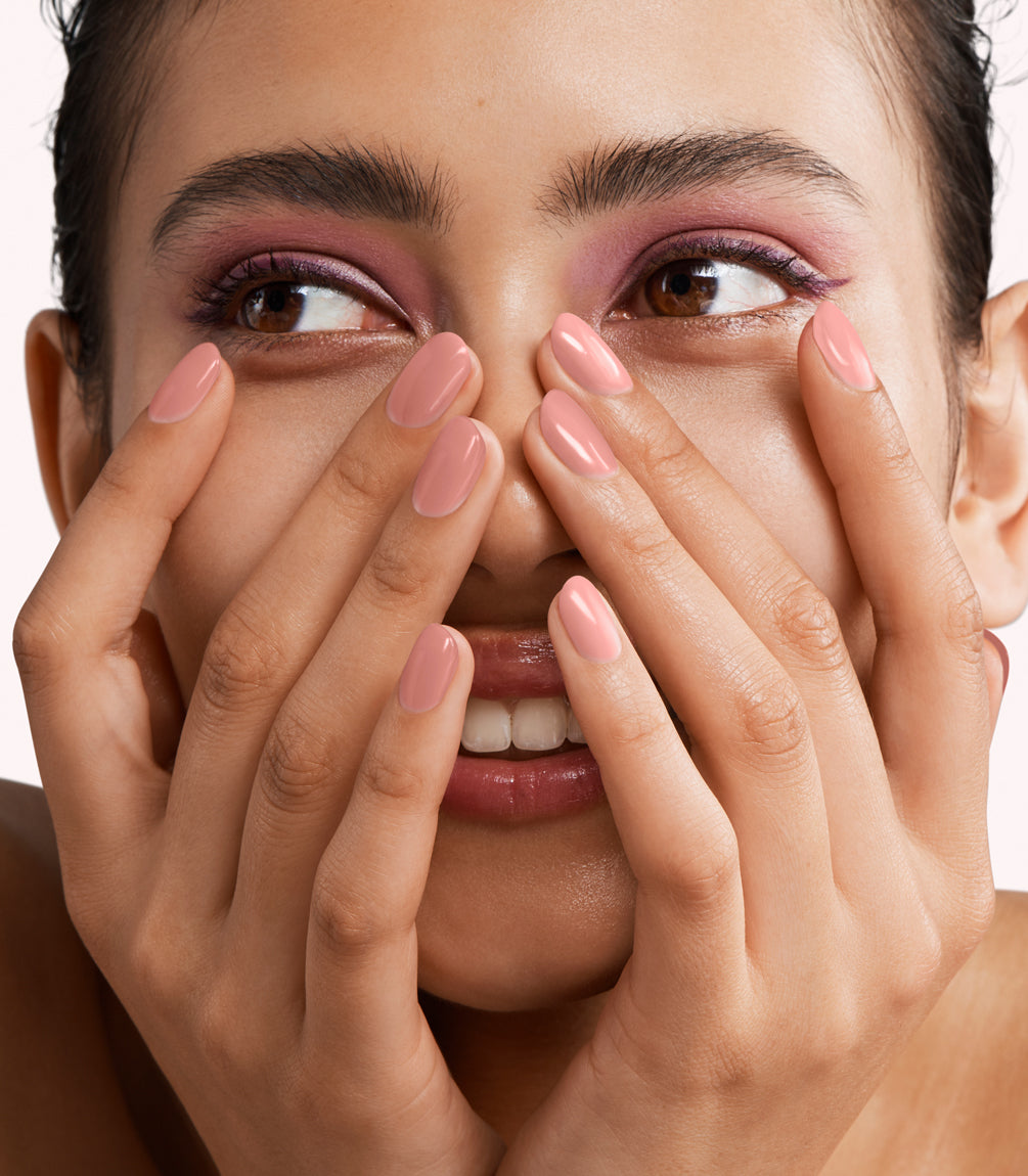 Close-up of a woman with Pink Gellac 399 Papaya Pink manicured nails near her face.
