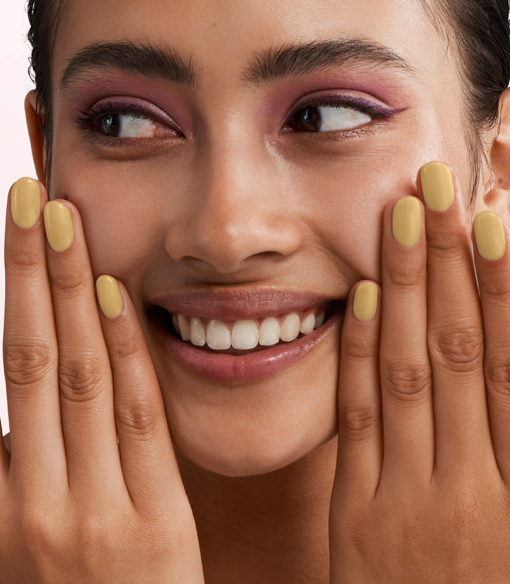Close-up of a woman with Pink Gellac 400 Seashell Gold manicured nails near her face.