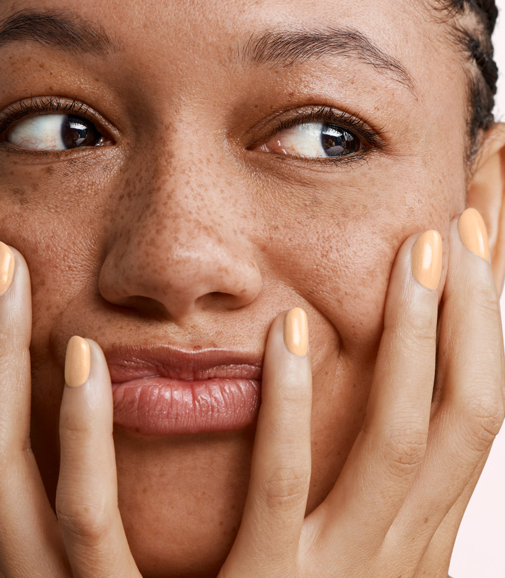 Close-up of a woman with Pink Gellac 408 Sorbet Peach manicured nails near her face.