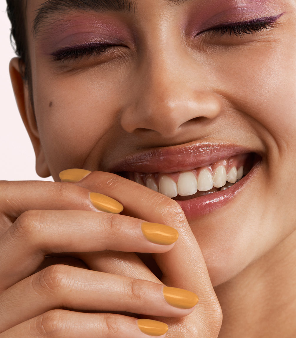 Close-up of a woman with Pink Gellac 409 Enchanted Apricot manicured nails near her face.