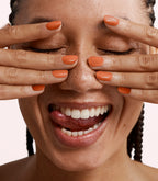 Close-up of a woman with Pink Gellac 410 Sunburst Red manicured nails near her face.