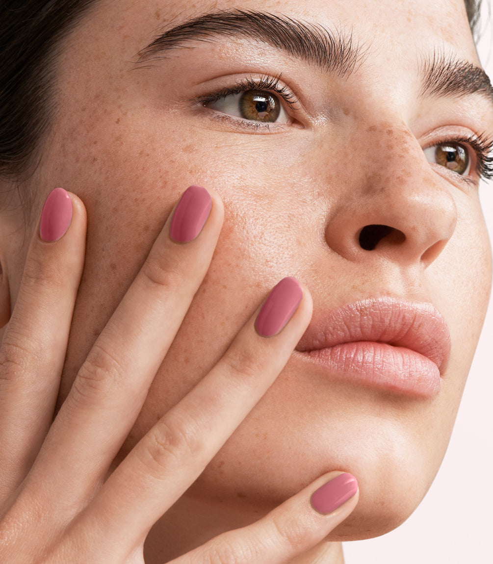 Close-up of a woman with Pink Gellac 424 Desert Rose manicured nails near her face.