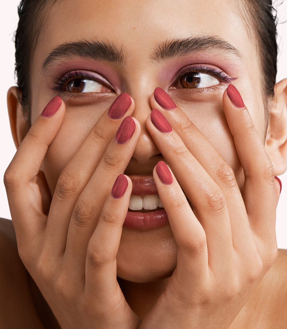 Close-up of a woman with Pink Gellac 425 Copper Crush manicured nails near her face.