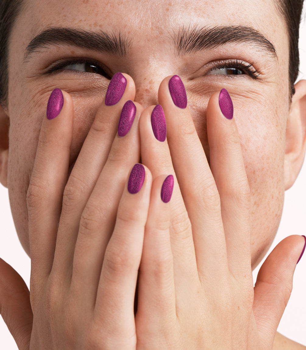 Close-up of a woman with Pink Gellac 426 Twinkling Plum manicured nails near her face.