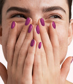 Close-up of a woman with Pink Gellac 426 Twinkling Plum manicured nails near her face.