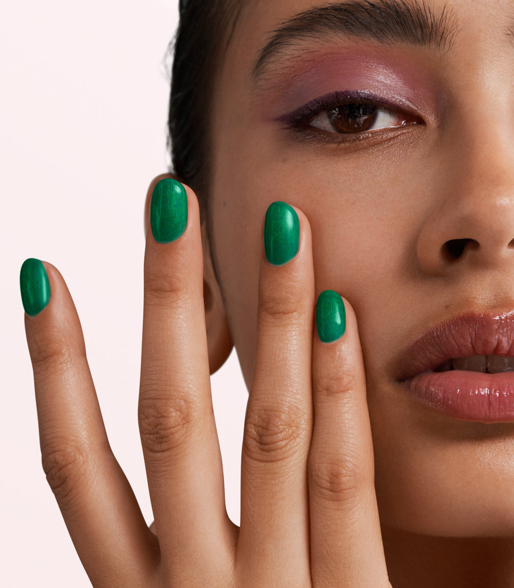 Close-up of a woman with Pink Gellac 428 Glamorous Green manicured nails near her face.