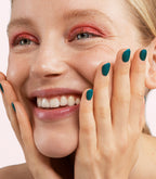 Close-up of a woman with Pink Gellac 429 Twinkling Emerald manicured nails near her face.