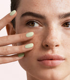 Close-up of a woman with Pink Gellac 443 Soft Pistachio manicured nails near her face.