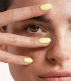 Close-up of a woman with Pink Gellac 445 Butter Yellow manicured nails near her face.