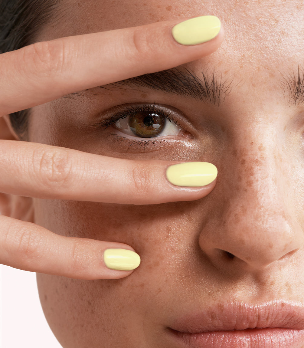 Close-up of a woman with Pink Gellac 445 Butter Yellow manicured nails near her face.