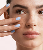 Close-up of a woman with Pink Gellac 451 Something Blue manicured nails near her face.