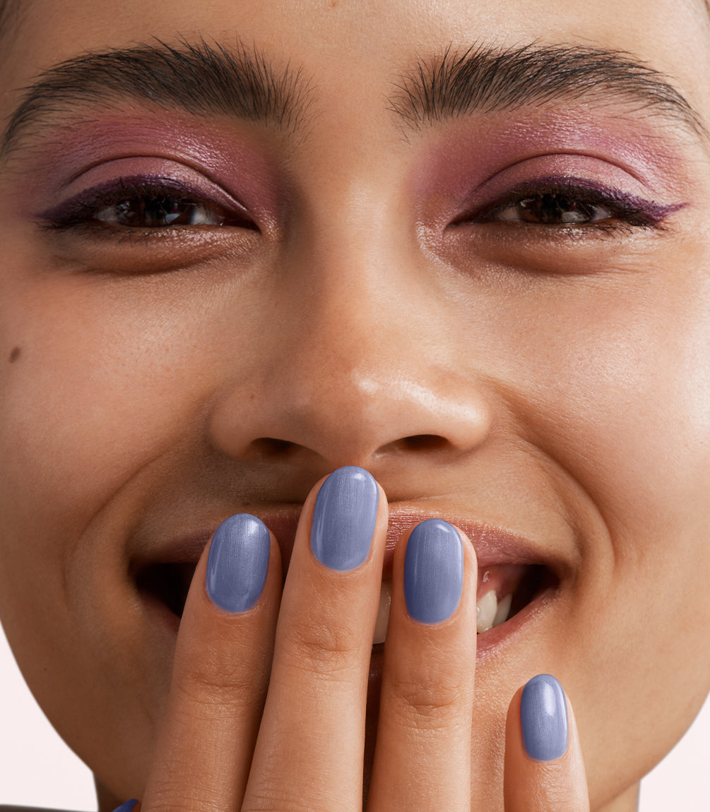 Close-up of a woman with Pink Gellac 456 Pearly Blue manicured nails near her face.
