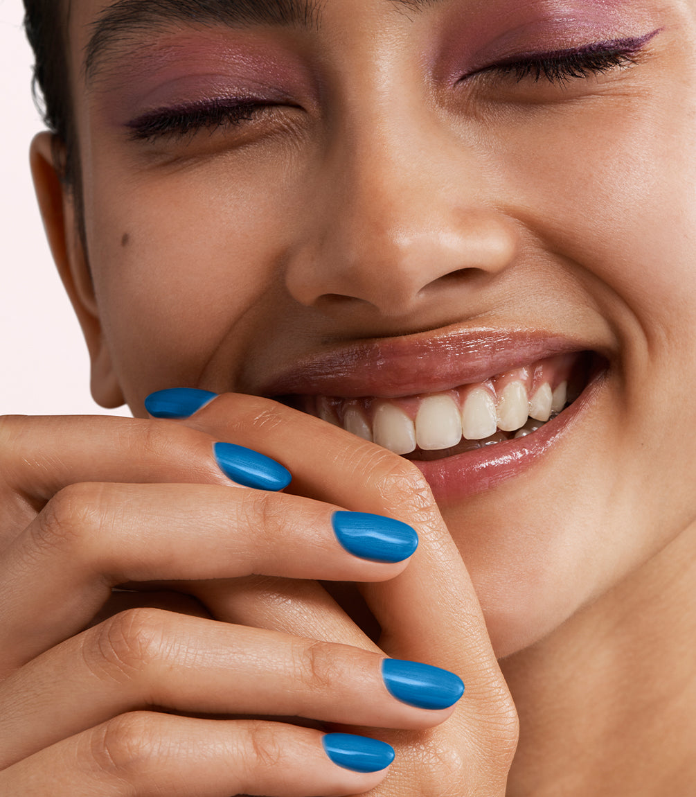Close-up of a woman with Pink Gellac 461 Metallic Blue manicured nails near her face.