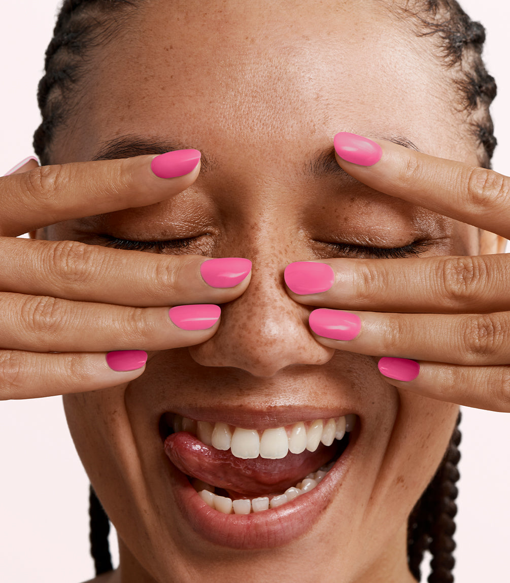 Close-up of a woman with Pink Gellac 462 Pink Rush manicured nails near her face.