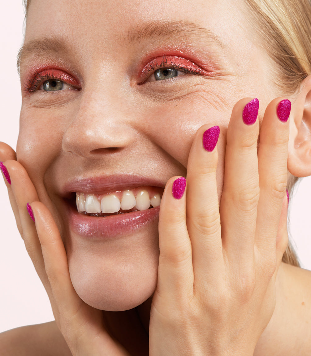 Close-up of a woman with Pink Gellac 463 Sparkling Magenta manicured nails near her face.