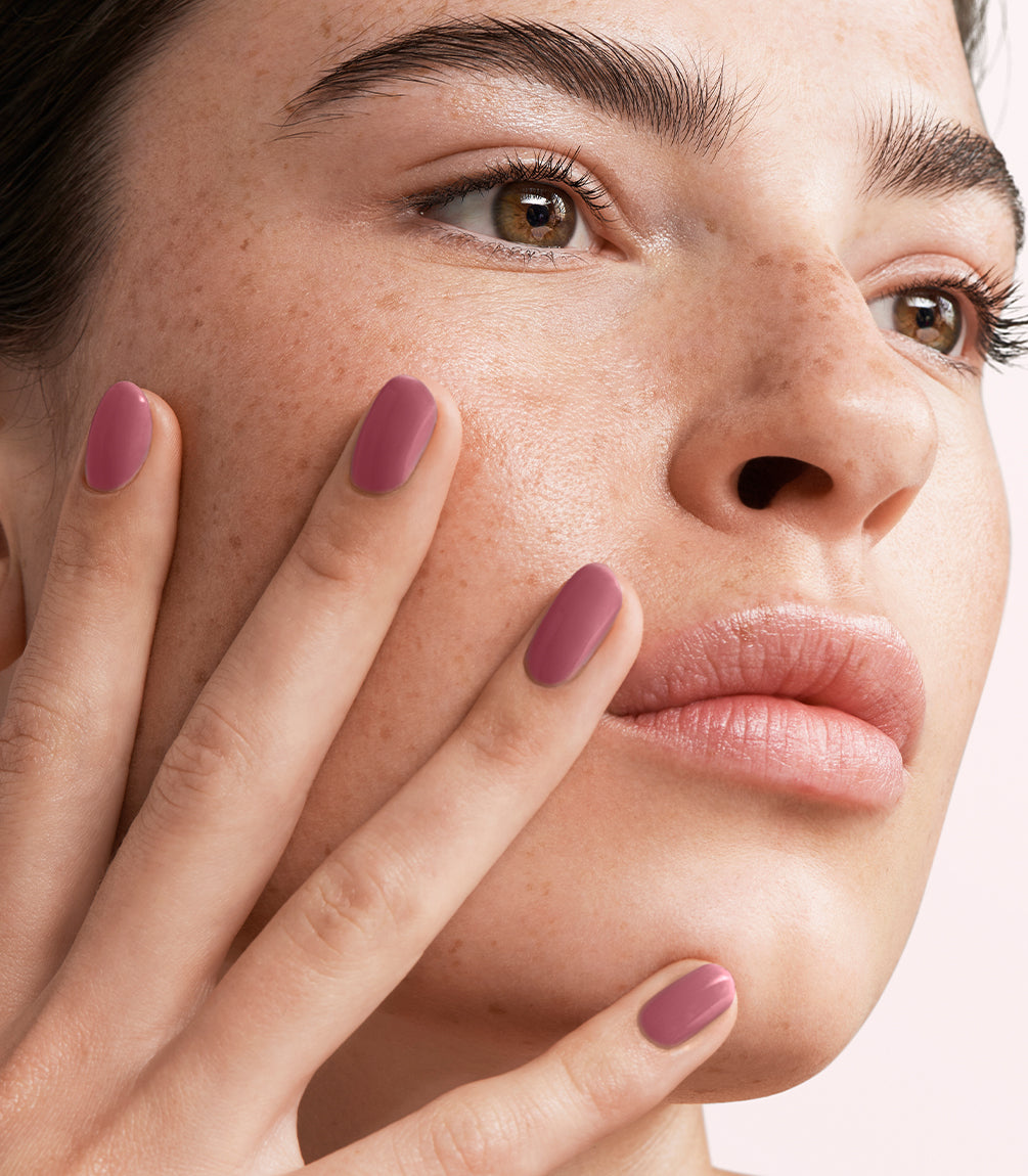 Close-up of a woman with Pink Gellac 467 Rosewood Haze manicured nails near her face.