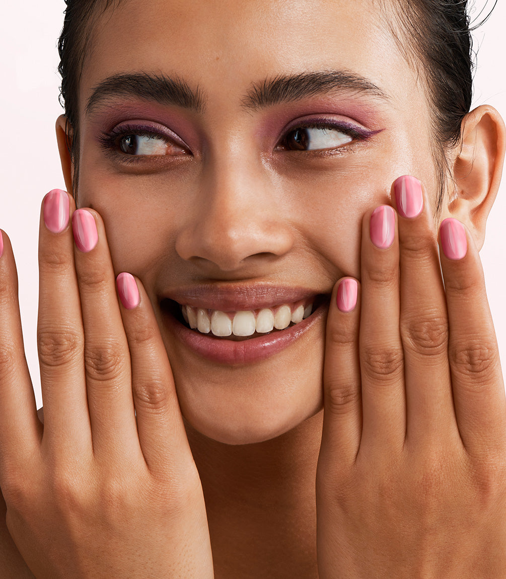 Close-up of a woman with Pink Gellac Jelly Coat Ballet Tint manicured nails near her face.