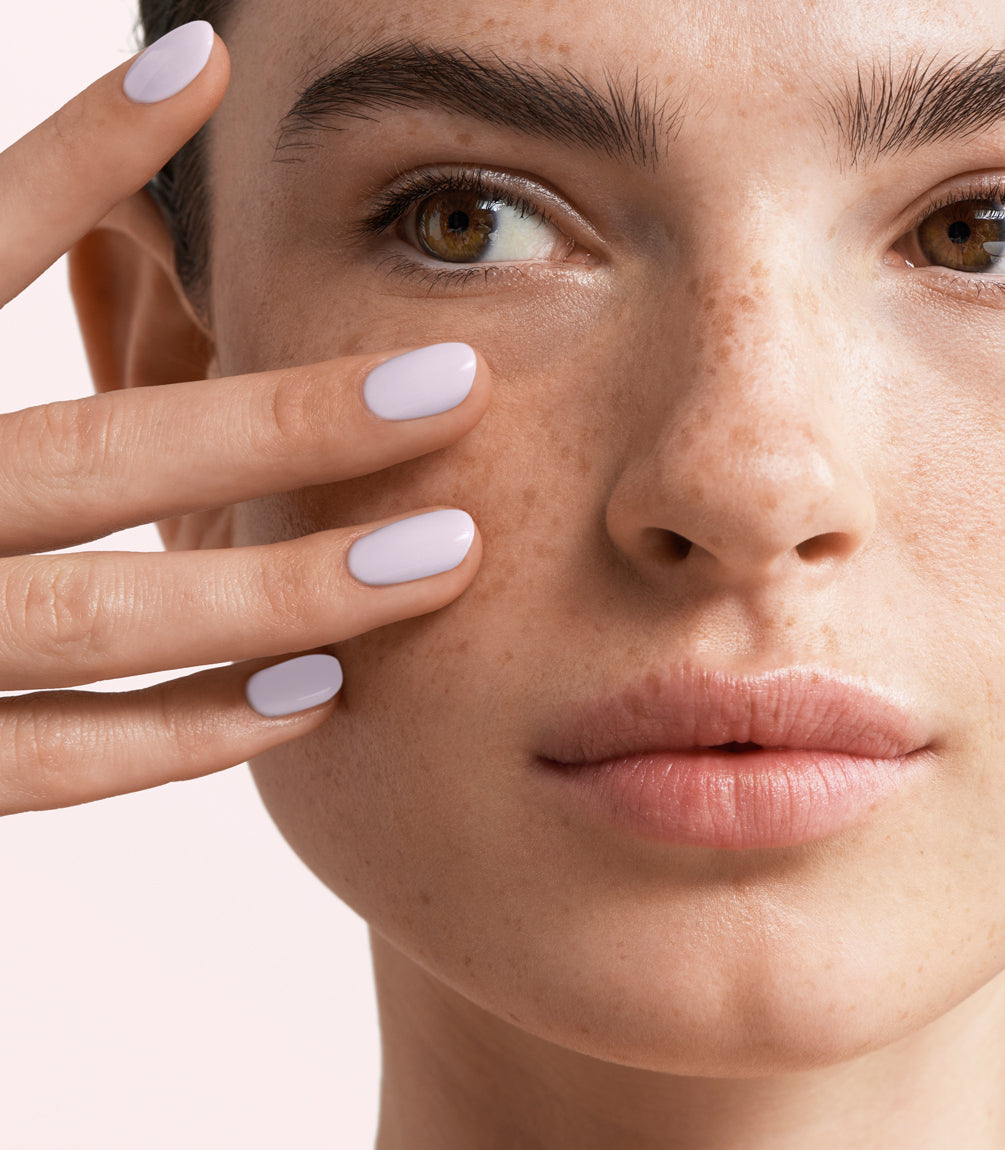 Close-up of a woman with Pink Gellac Rubber Base Cover Frozen Lilac manicured nails near her face.