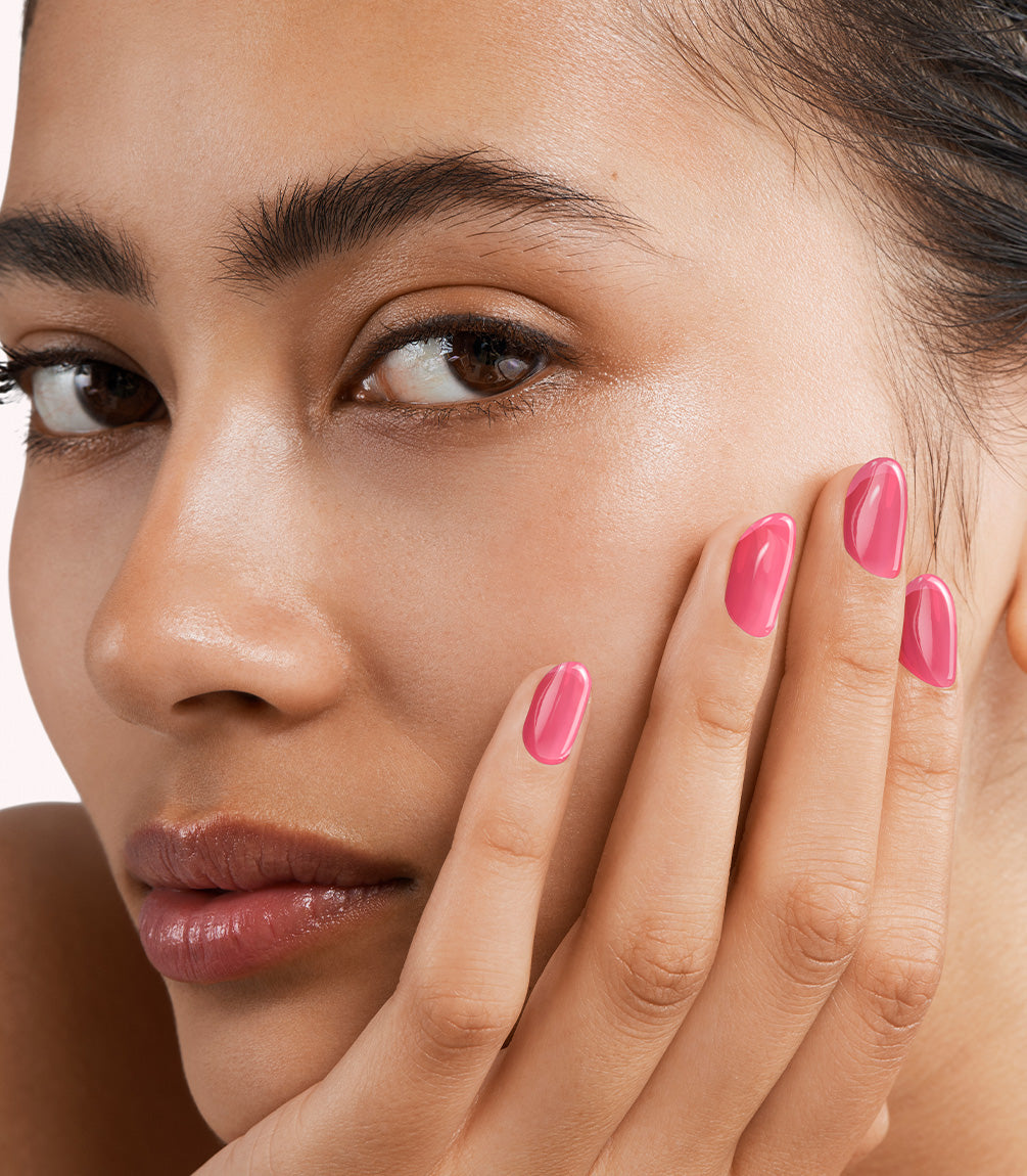 Close-up of a woman with Pink Gellac Jelly Coat Ruby Gloss manicured nails near her face.