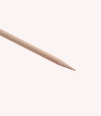 A wooden toothpick with a sharp point against a white background.